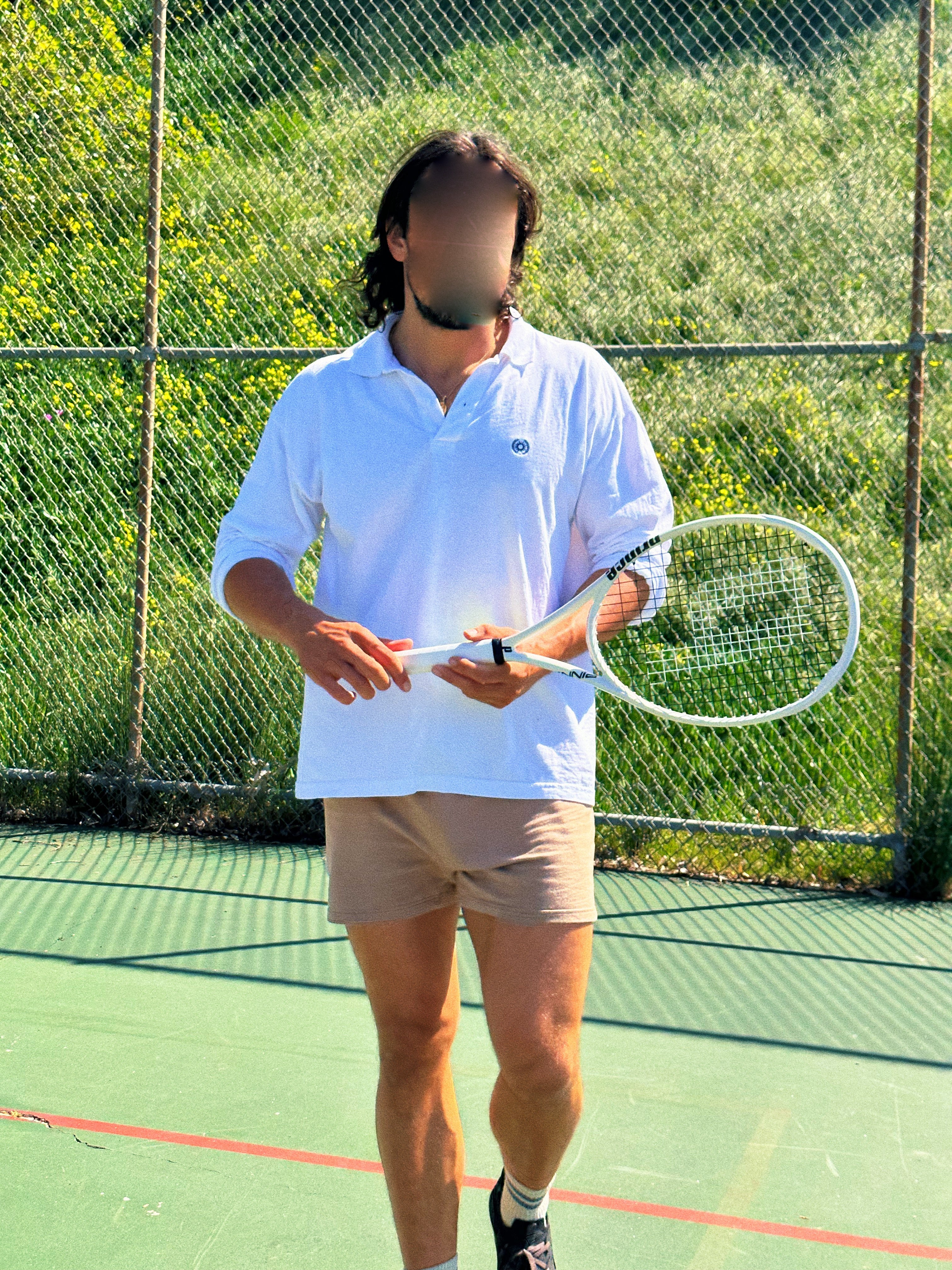 man holding tennis racket on a tennis court and wearing a white polo tshirt made of cotton 