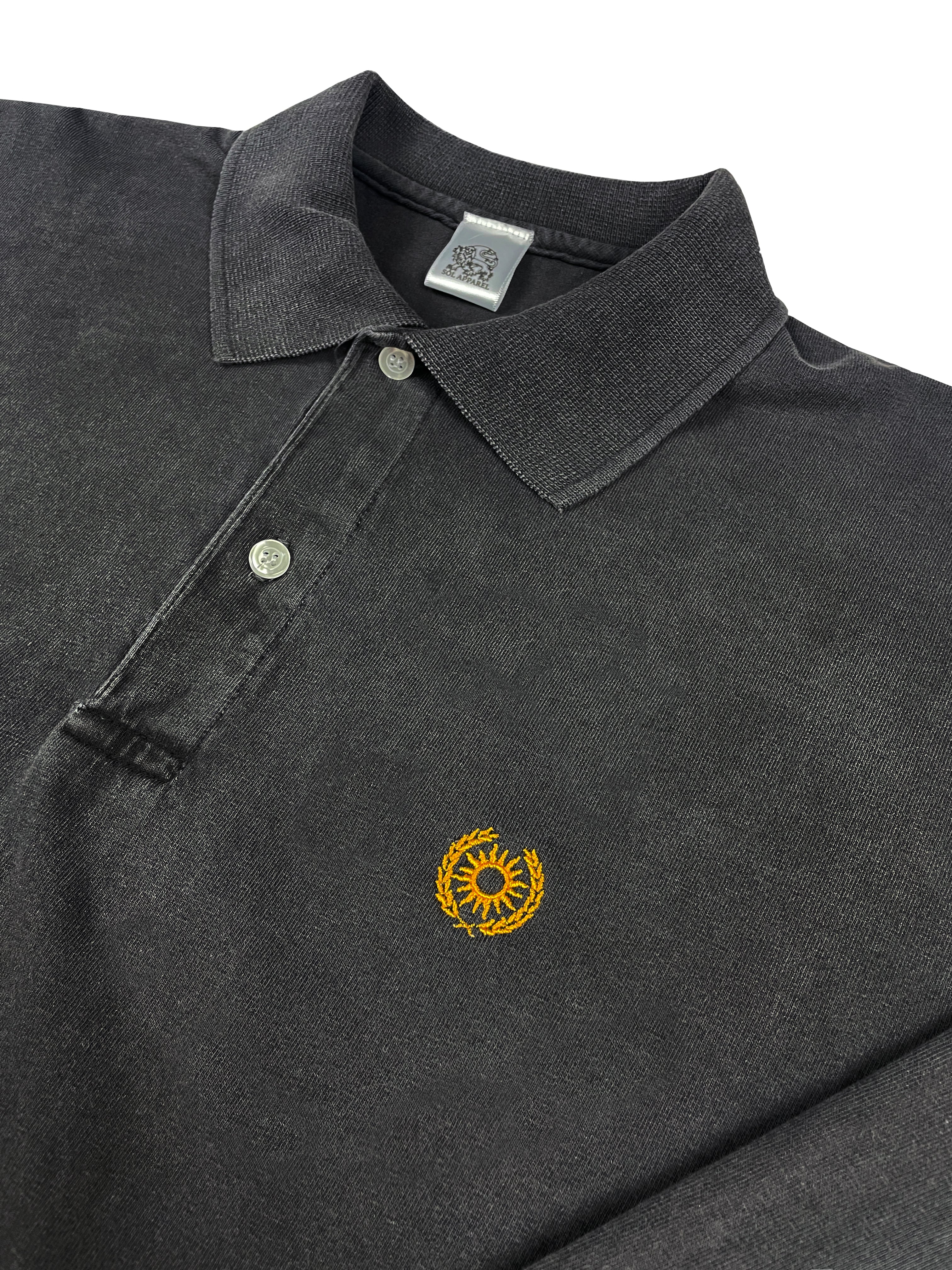 close up of black cotton polo tshirt with a golden sun and laurels embroidered on the left chest