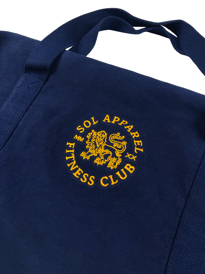 closeup of sol apparel fitness club navy colored duffel bag with gold embroidered logo