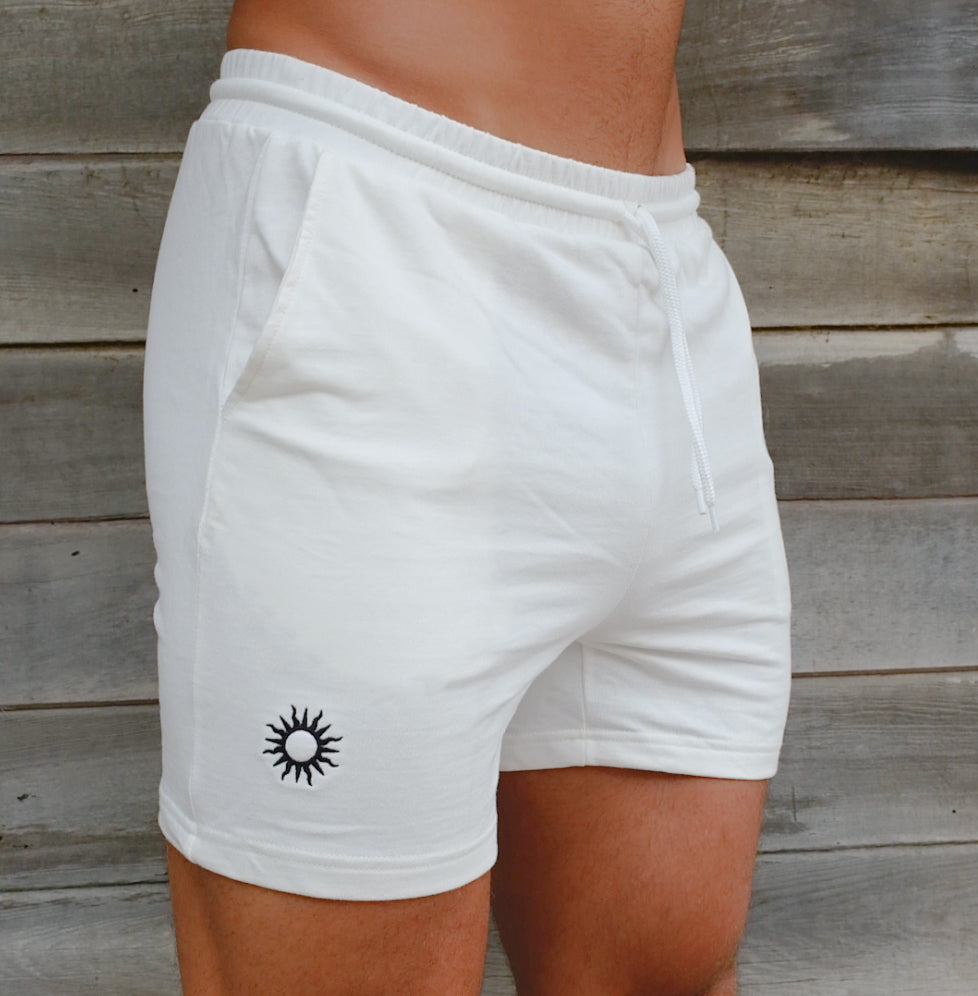 close up on man wearing white cotton gym shorts for men with pockets and embroidered with the black sun logo