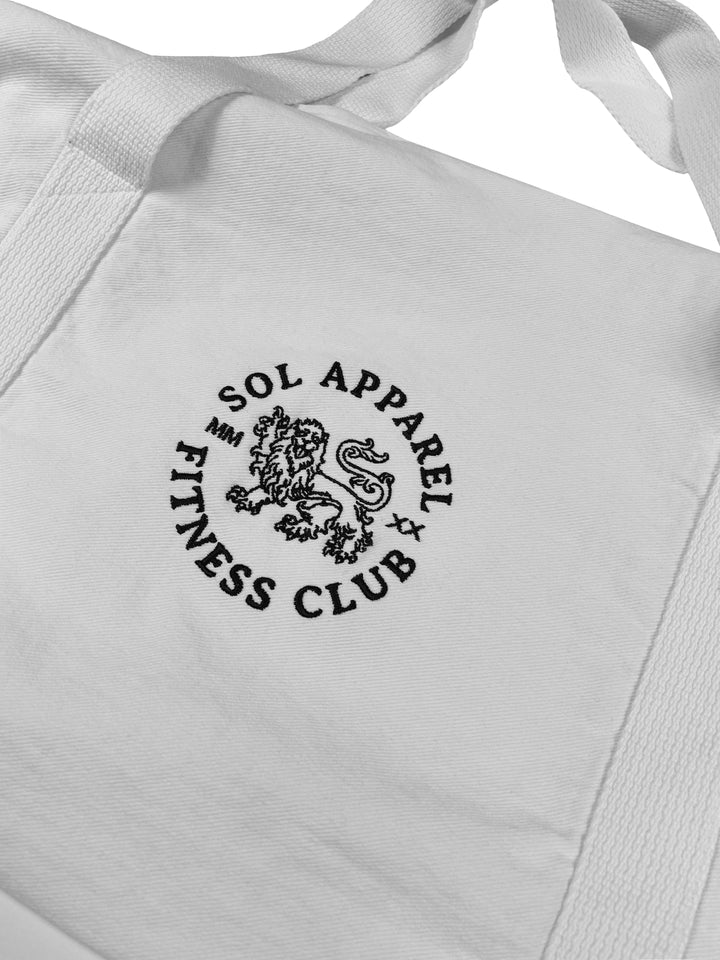 close up of white gym duffel bag in cotton with embroidered logo of lion and the text sol apparel fitness club
